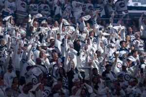 Des partisans des Jets de Winnipeg en chandails blancs agitent des serviettes