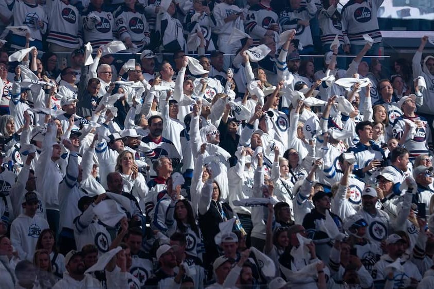Des partisans des Jets de Winnipeg en chandails blancs agitent des serviettes